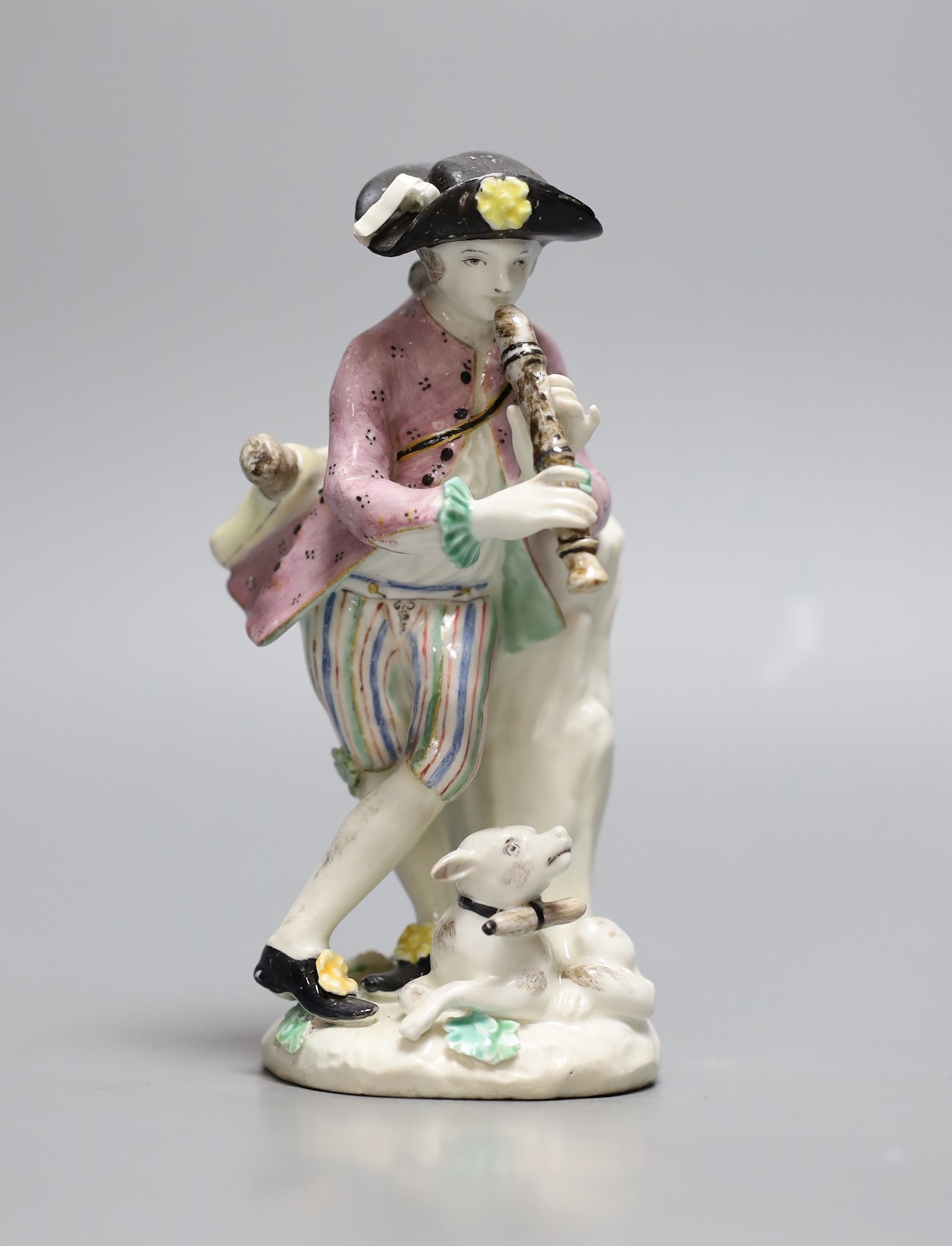 A Bow figure of a boy with dog playing the pipes, 25.5 cms high